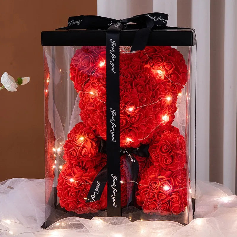 Red rose bear with LED lights in a clear box with a black ribbon on a white background.